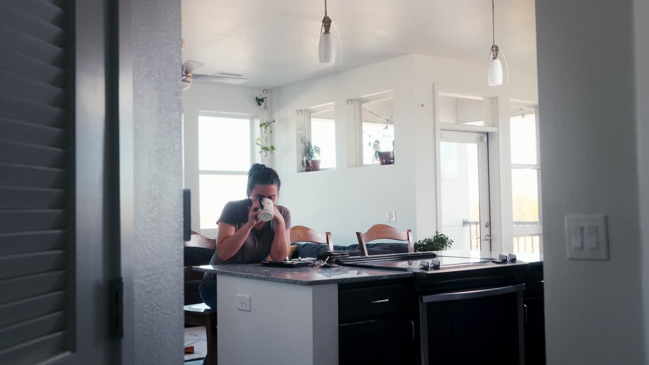 toma amplia de una hermosa mujer caucásica milenaria desliza lentamente una taza de café por la mañana mientras está sentada en su cocina y comedor