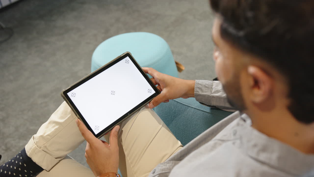 Holding tablet, Indian man working on blank screen in modern office setting