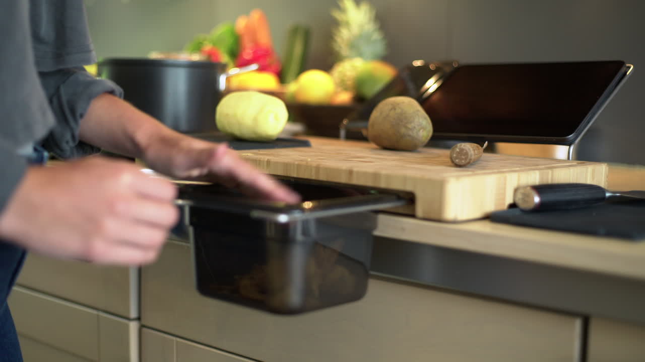 cerca de manos femeninas barriendo la piel de patata en bin