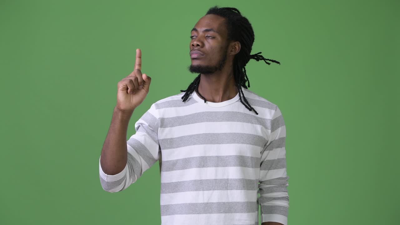 Young handsome African man with dreadlocks against green background