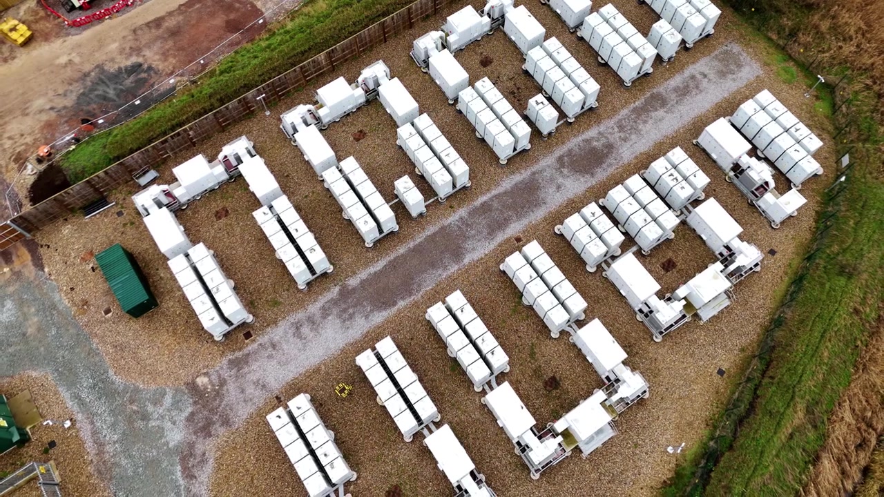 Drone shot of critical power infrastructure featuring large-scale lithium battery storage units in rural Burwell, England.