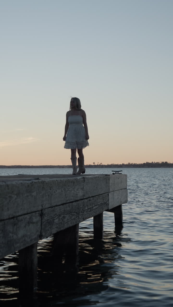 Bella ragazza che si allontana da un molo al tramonto.