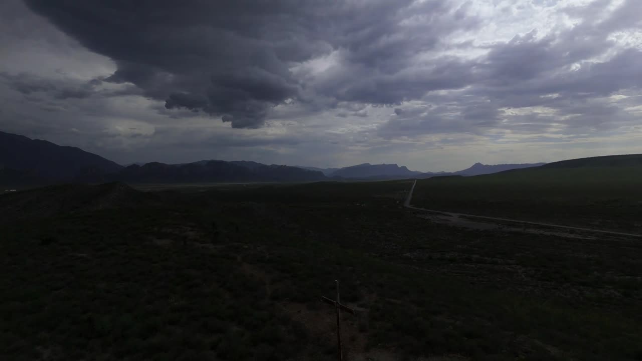 Christian cross on top of a hill with a cloudy and slightly dark sky but at the same time with light showing a feeling of what Christian doctrine is but with a reverse shot or back 4k 60 fps