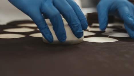 baker cutting out circles of cookie dough, close up of hands