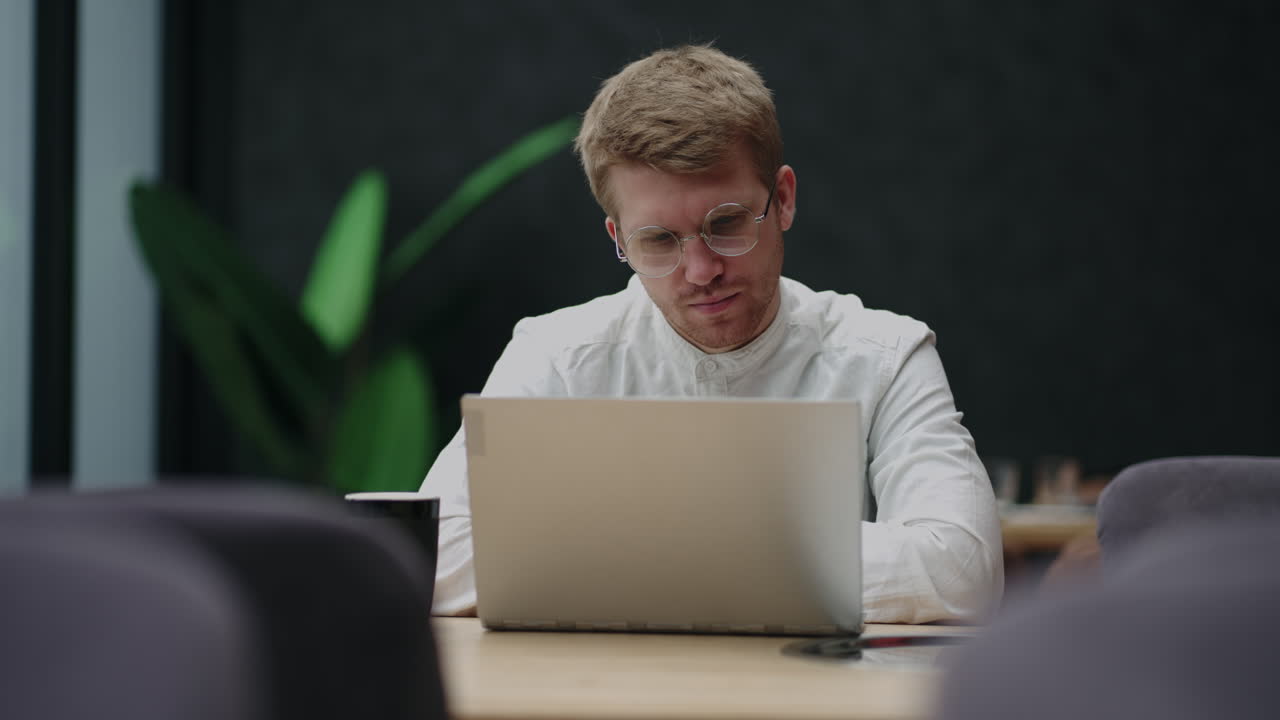 Attentive millennial male manager employee busy at telework at quarantine time study documents in corporate network from home pc. Concentrated young man specialist doing remote computer work on laptop