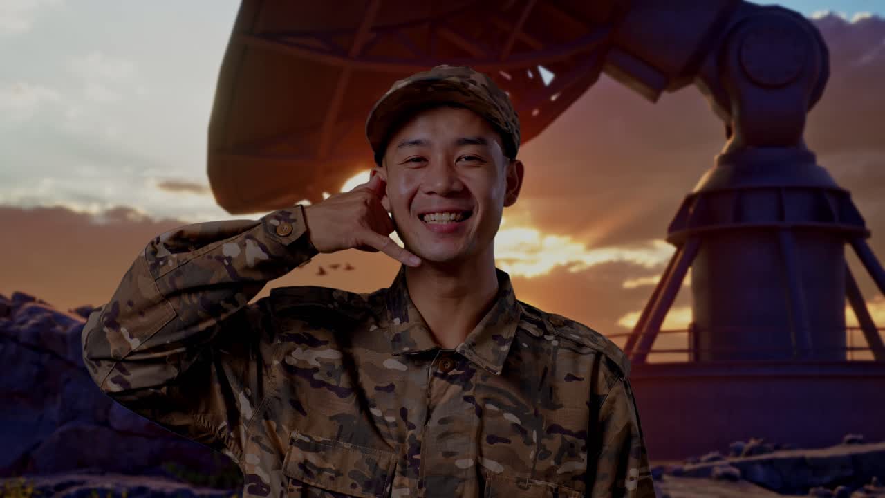 Close Up Of Asian Man Soldier Smiling And Making Call Me Gesture To Camera While Standing With Satellite Dish