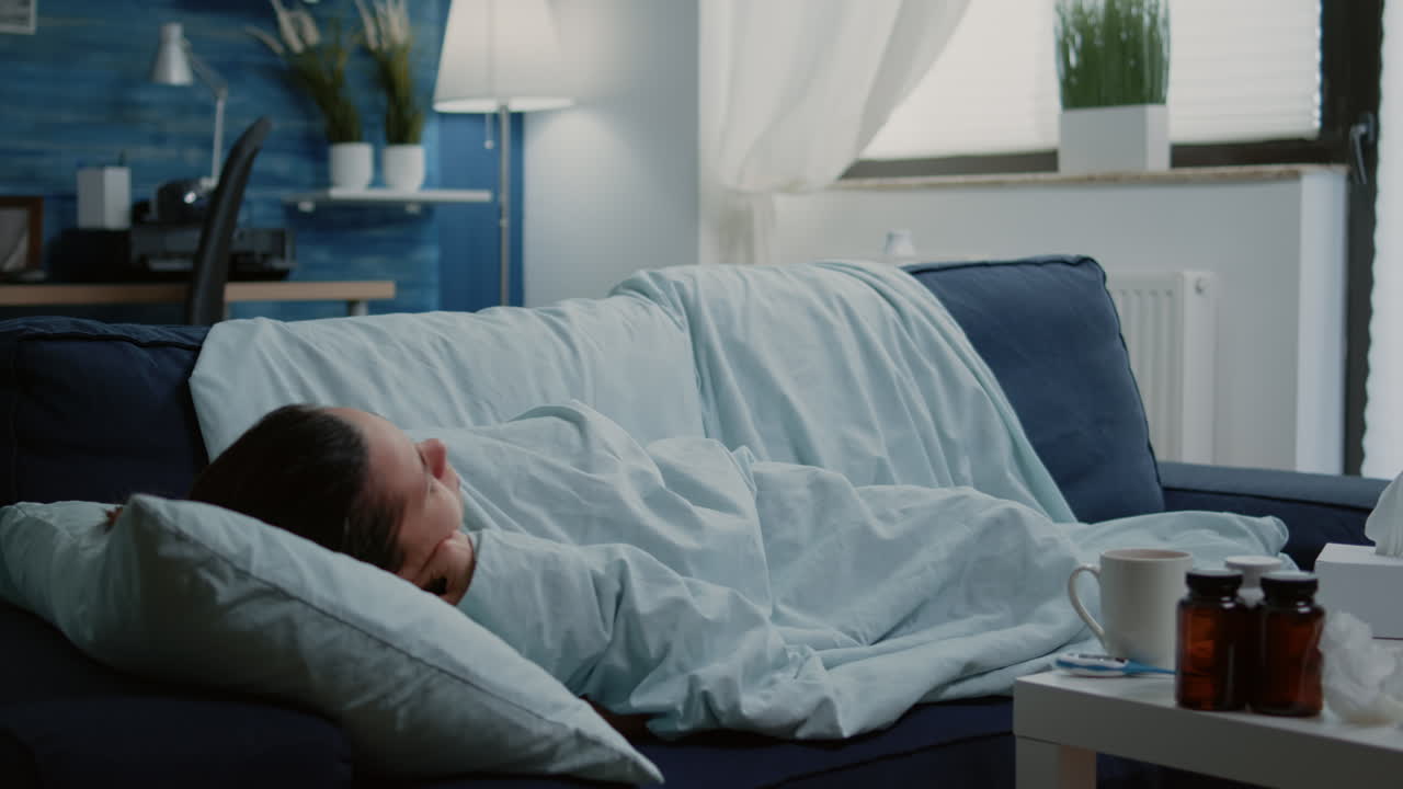 Woman with disease laying on couch and measuring fever