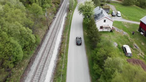 aerial view of a car driving on a country road next to a railway