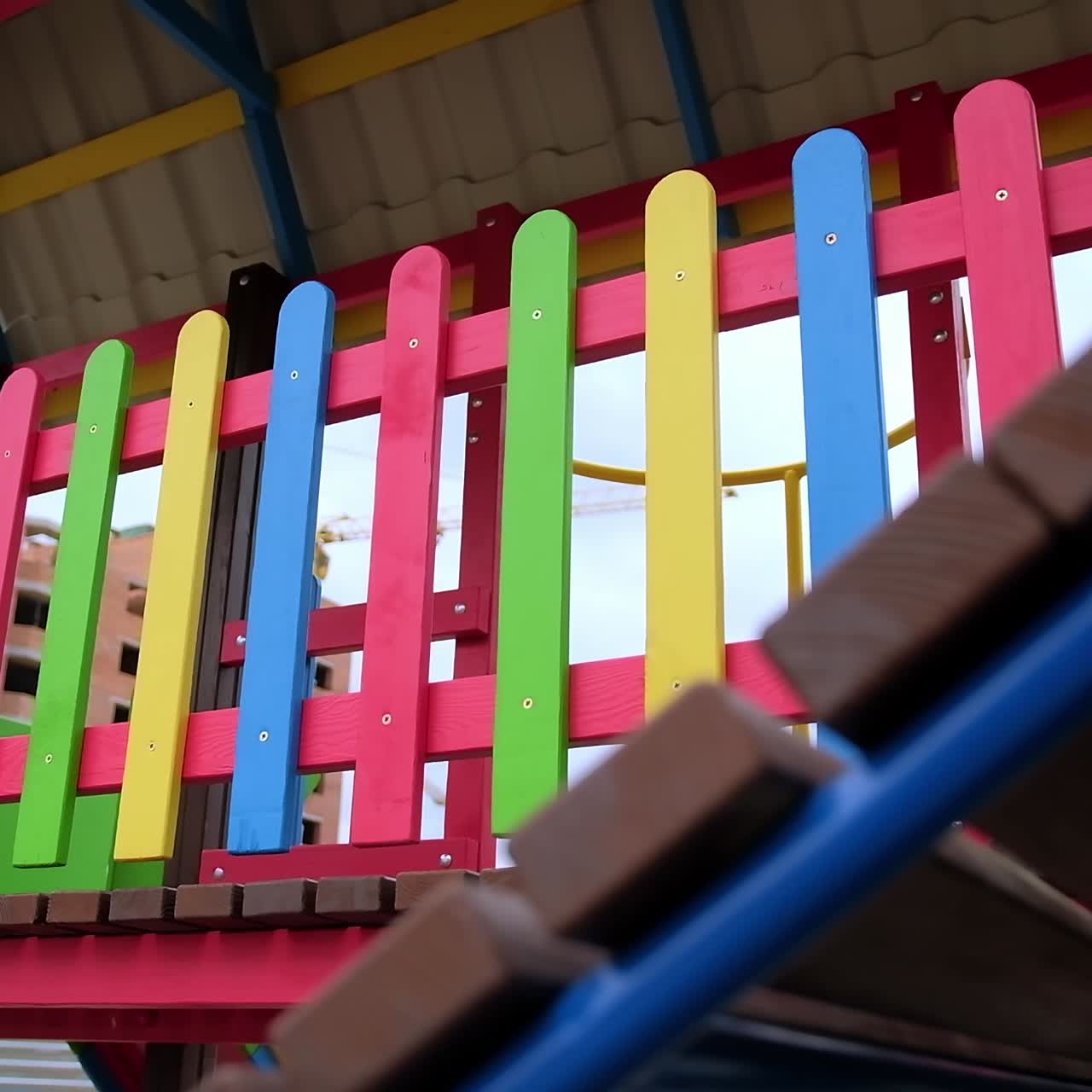 Multicolored wooden fence on the children's playground. Passages, slides and ladders in the residential area