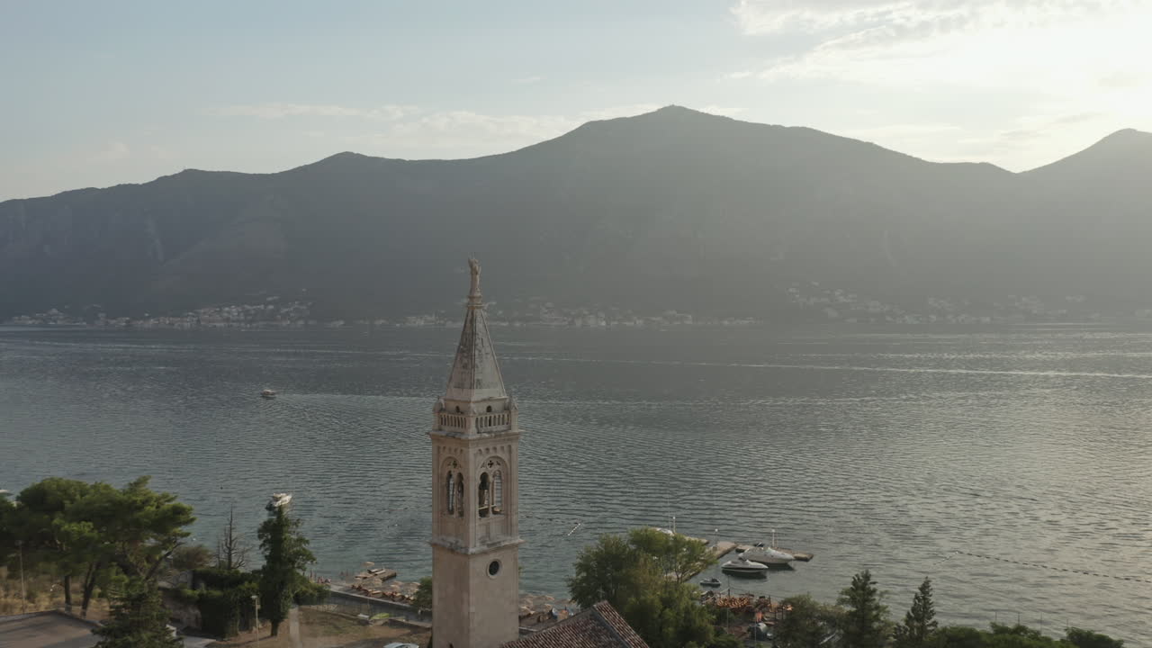 Drone parallax shot around the spire of the Church of Saint Eustace with a view of the bay in Kotor Montenegro