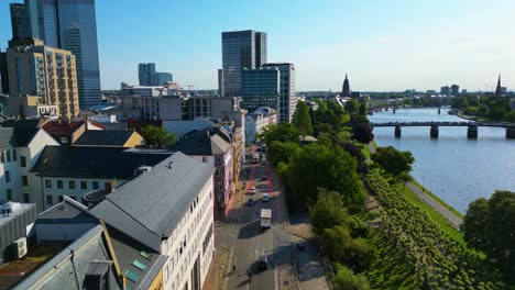 4k aerial drone video of the historic buildings along the main river near the liegewiese mainufer park in downtown frankfurt, germany