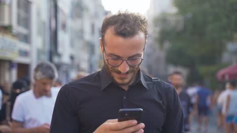 hombre usando el teléfono entre la multitud riendo.