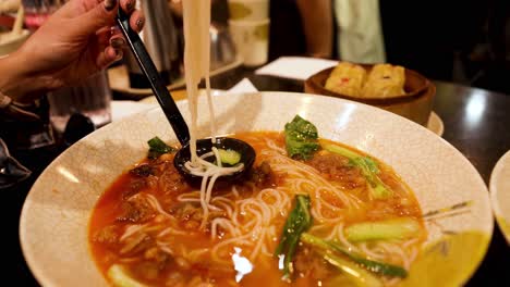 person eating noodles with chopsticks in melbourne