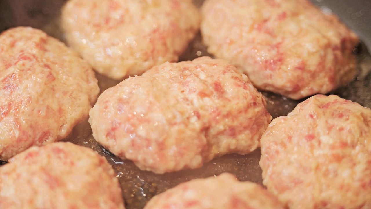 Rack focus shifts across sizzling cutlets, emphasizing texture, home cooking