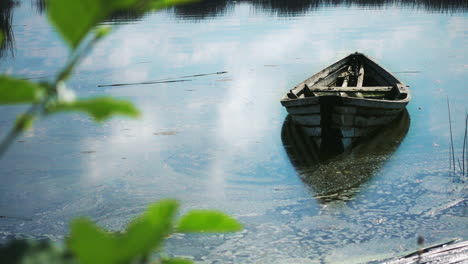 rural landscape with old fishing boat on lake. old wooden boat on water