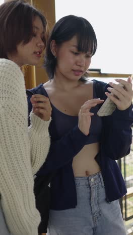 two asian women looking at a phone