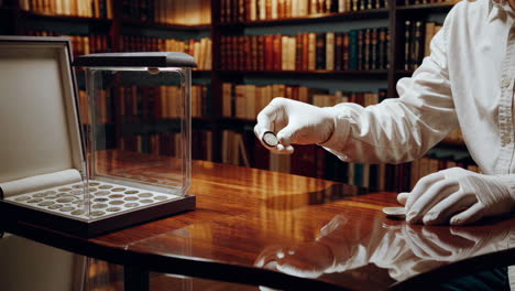 expert examining rare coins in a library setting