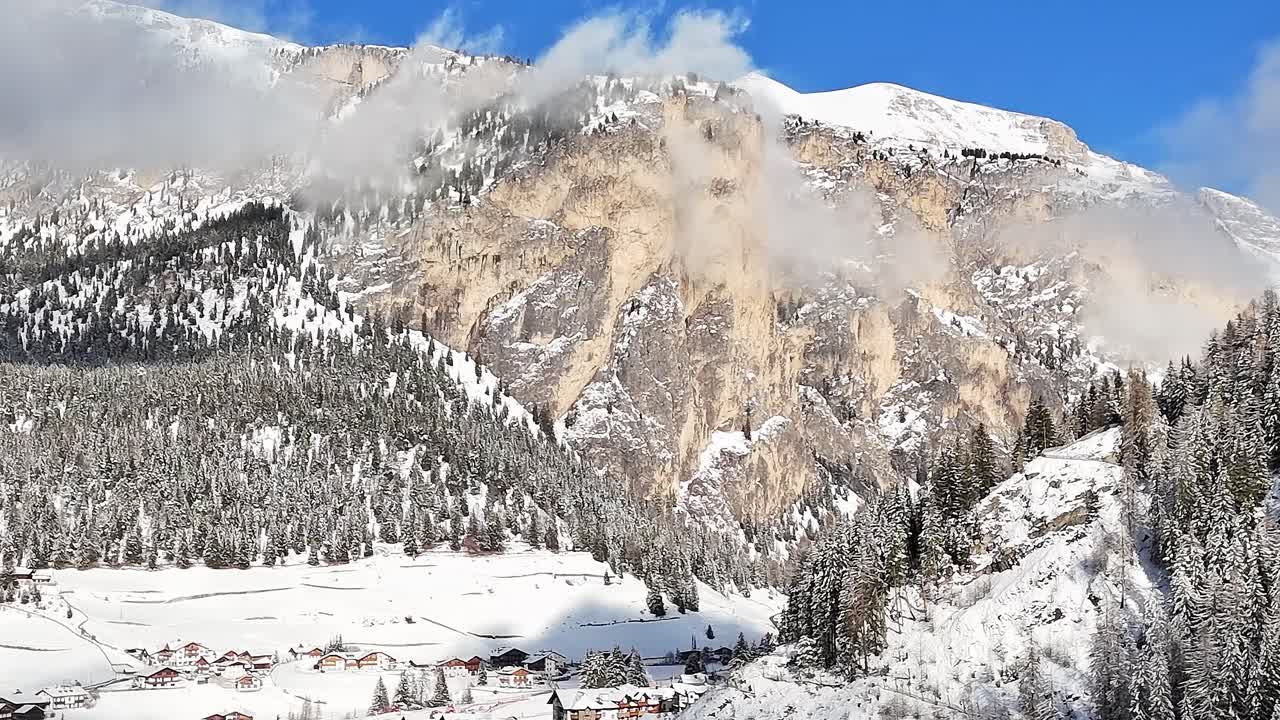 Alpi italiane innevate con alberi e montagne sotto un cielo sereno