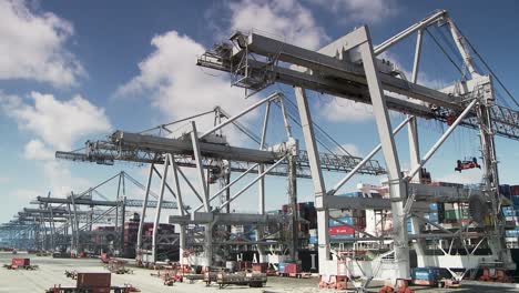 big harbour container cranes lifting goods on ship for export, static wide shot