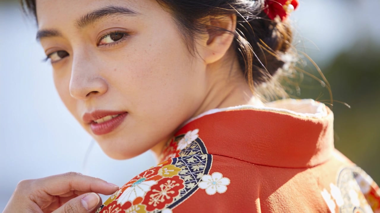 Donna asiatica che si gira, telecamera che riprende, che tocca il kimono, che posa e guarda la telecamera in giardino con spille.