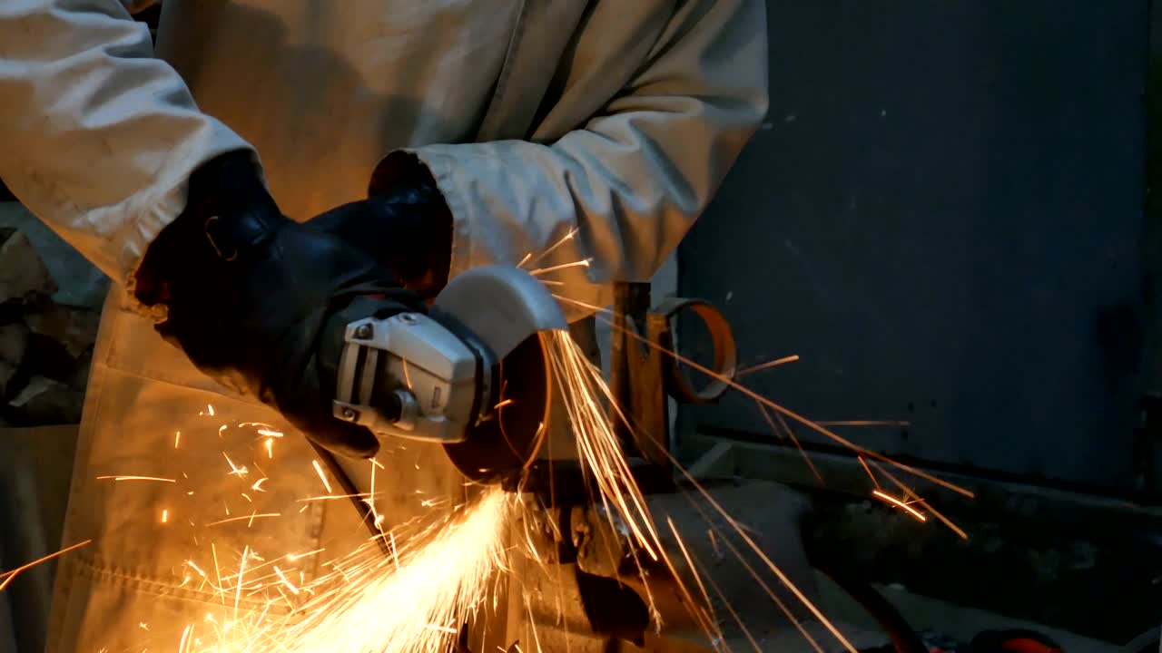 un hombre corta metal con una molienda en su taller. el pasatiempo de un hombre. 4k