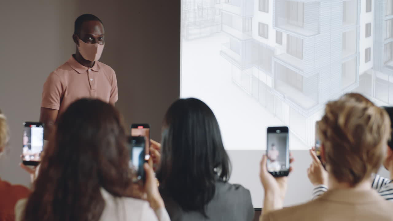 마스크 를 입은 아프리카계 미국인 강연자 가 컨퍼런스 에 대한 발표 를 하고 있다