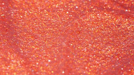 mixing vibrant orange ink and glitter in a close-up macro shot creating an abstract scene