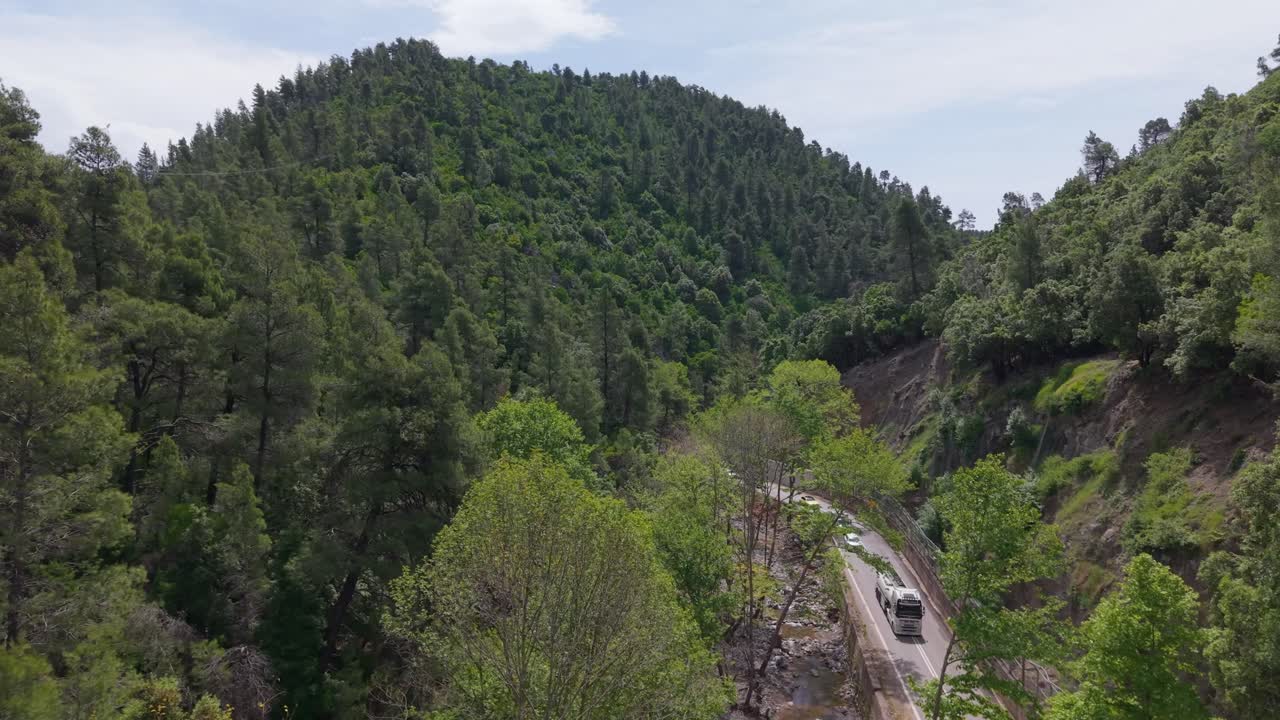 Aerial view of a mountain road with light traffic winding through a gorge in North Evia, surrounded by dramatic cliffs and lush natural scenery