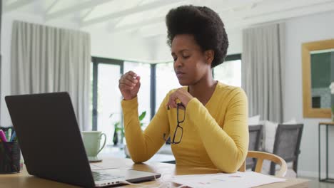 Tired-african-american-woman-sitting-at-table-using-laptop