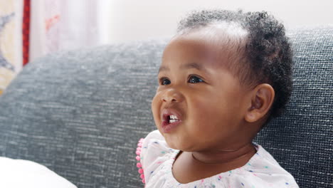 Cute-Baby-Girl-Sitting-On-Sofa-At-Home