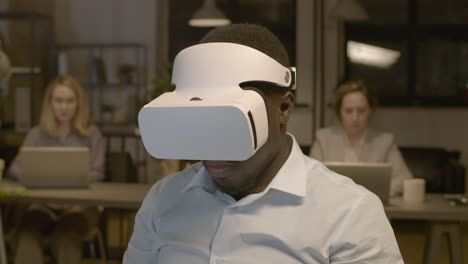 close up view of american man sitting at desk in the office moving hands and wearing virtual reality glasses