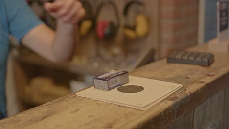 Hand-placing-shooting-targets-and-a-box-of-ammunition-on-a-counter