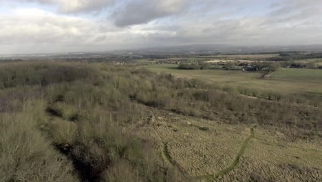 idyllic british farming meadows countryside fields aerial view pull back over green trees landscape