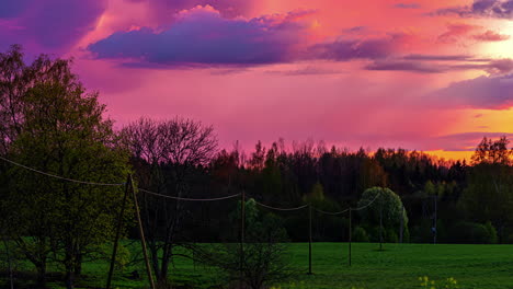 Time-lapse-of-a-fiery-sunset-with-fast-moving-clouds-over-a-green-nature-landscape