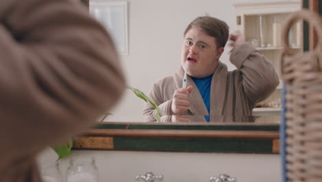 funny teenage boy with down syndrome singing in bathroom having fun enjoying morning routine getting ready wearing bathrobe