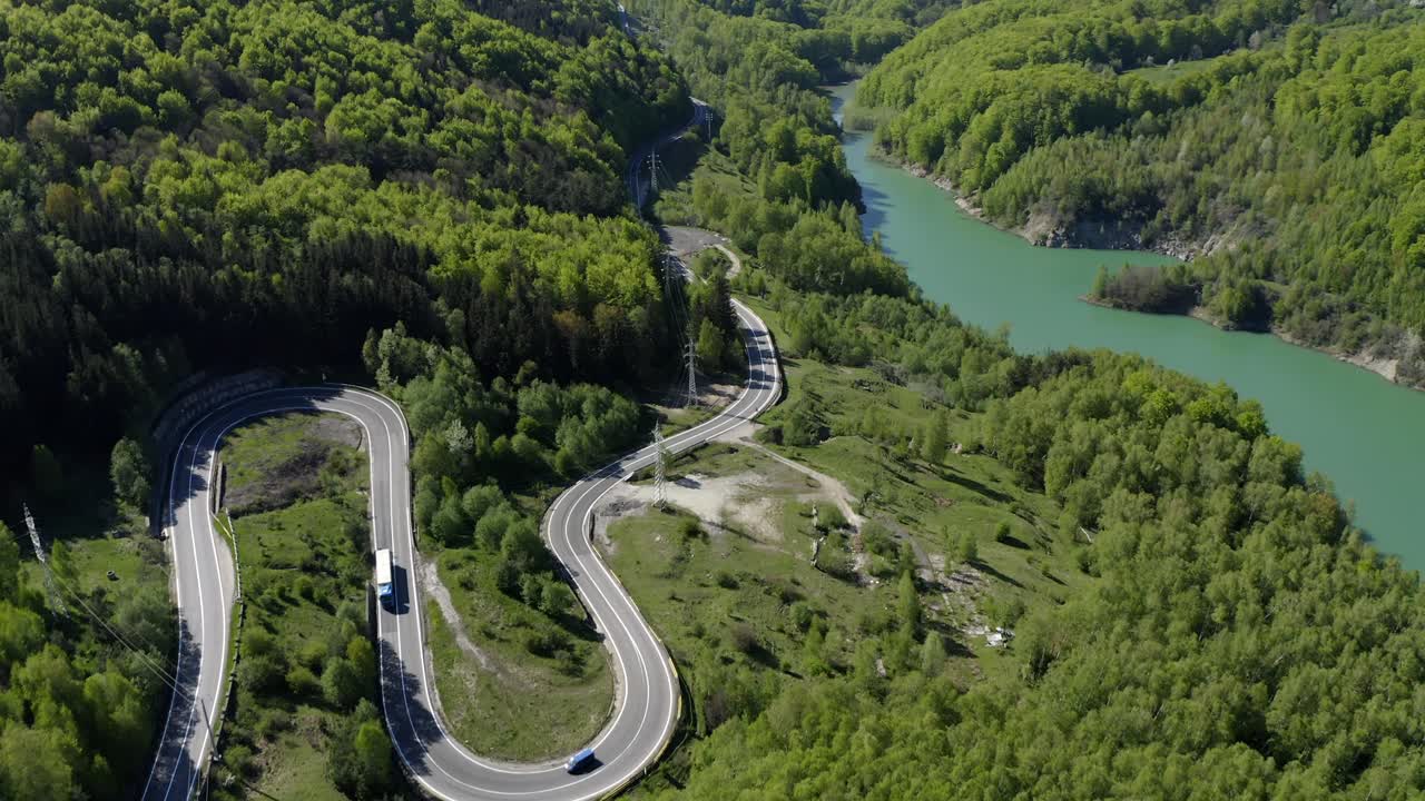 vista aérea de la sinuosa carretera de montaña a través del bosque a orillas del lago