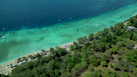 bird-eye-view-of-the-beach's-shore-with-turquoise-sea-water-mixing-with-dark-blue-water-and-the-trees-of-the-Gli-Trawangan-island-in-Indonesia