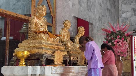 people praying at a golden buddhist temple in thailand