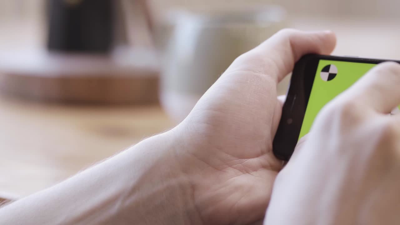 녹색 화면과 캘리브레이션 마크를 가진 스마트폰을 들고 있는 사람