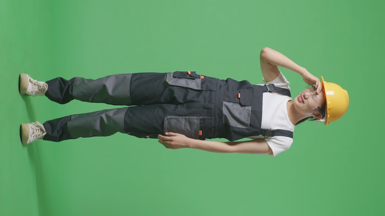Full Body Of Asian Woman Worker Wearing Goggles And Safety Helmet Having A Headache While Standing In The Green Screen Background Studio