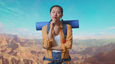 asian female hiker with mountaineering backpack thinking about something and looking around while traveling at the top of mountain
