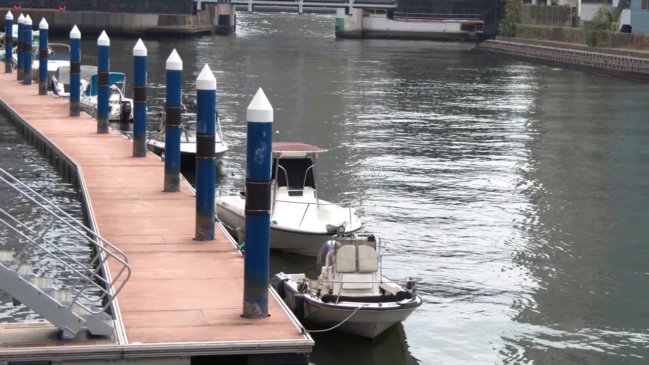 Static high-angle shot of small boats docked at a wooden pier in Tokyo, Japan.