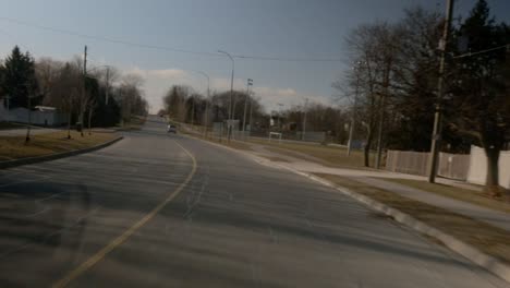 Driving-through-a-suburban-neighbourhood,-a-sports-field-is-in-the-distance