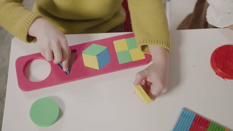 vista superior de un niño jugando con un clasificador de formas mientras está sentado en el escritorio en una escuela montessori 1