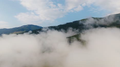 drone shot flying over a cloudy valley looking into yoho national park in british columbia canada with green mountainsides visible in summer