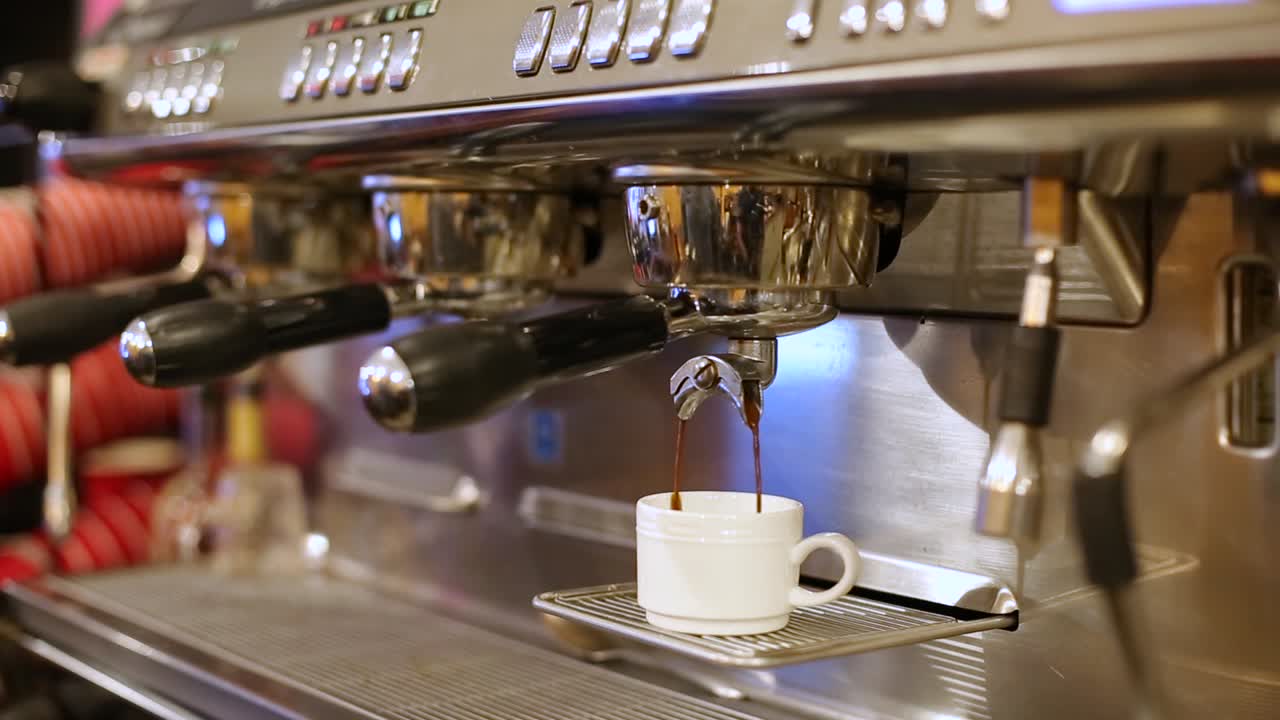un primer plano de una máquina que vierte espresso en una taza blanca