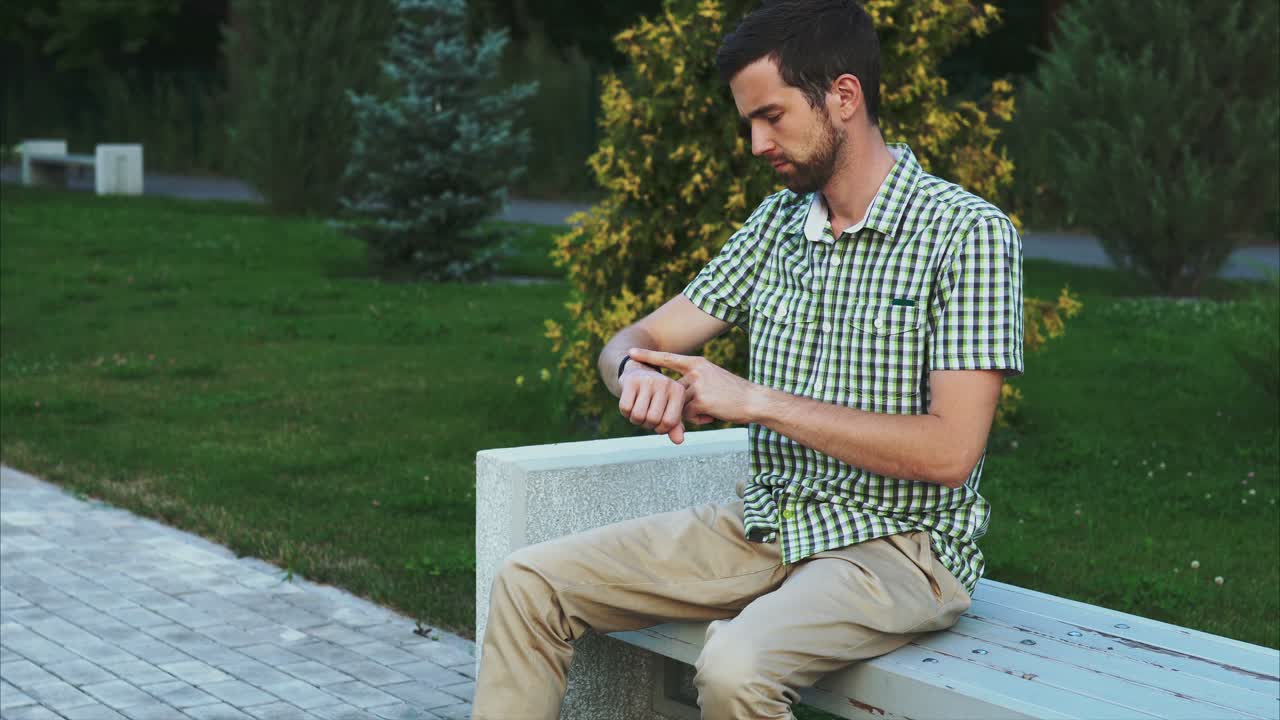 hombre comprobando el tiempo en un banco en el parque