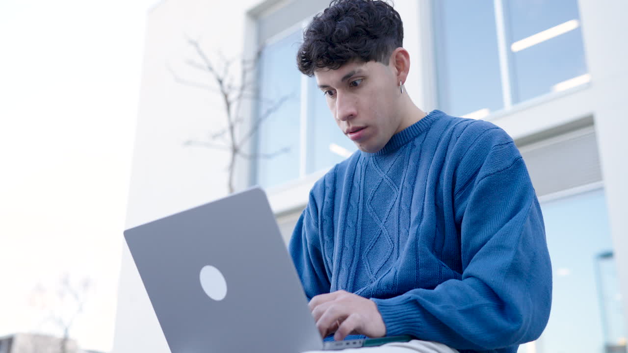 Young man using netbook celebrating success outdoors