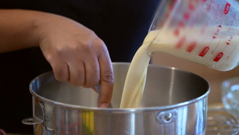 pouring milk into a mixing bowl to make a tasty homemade treat - stirring in the ingredients in slow motion, side view