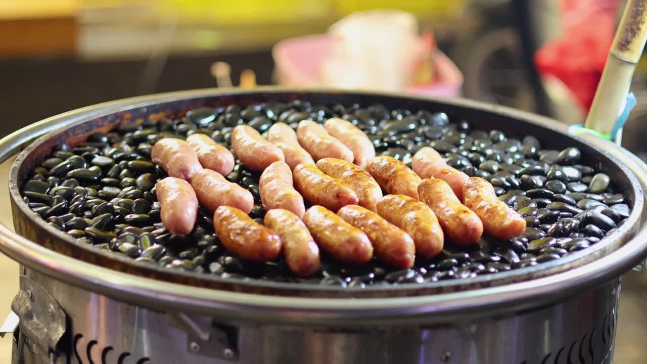 소시지가 그릴 위에 뜨거운 돌을 돌리고 있다